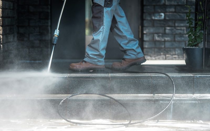 Pressure Washer Cleaning Time. Men Cleaning Outside House Stairs with Power High Pressured Cleaner. Ceramic Stairs and Home Entrance. Closeup Photo.